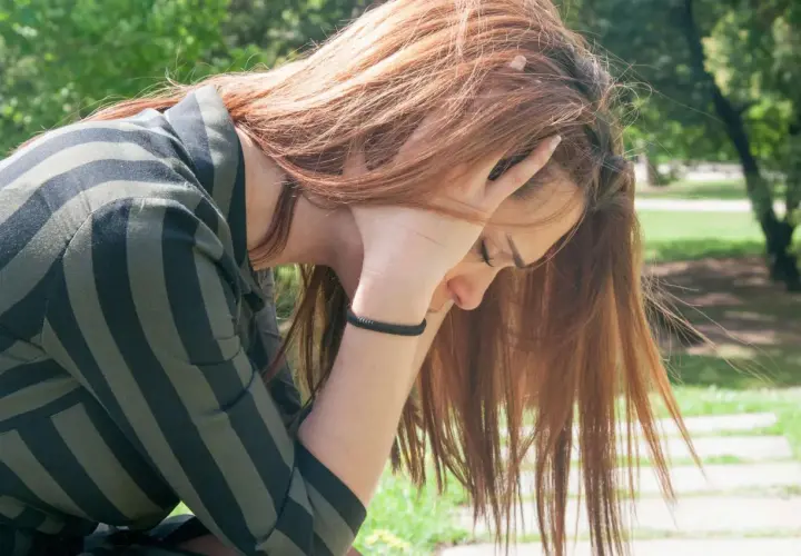 Ragazza con capelli rossi, mani tra i capelli, in cerca di tricotillomania rimedi naturali.