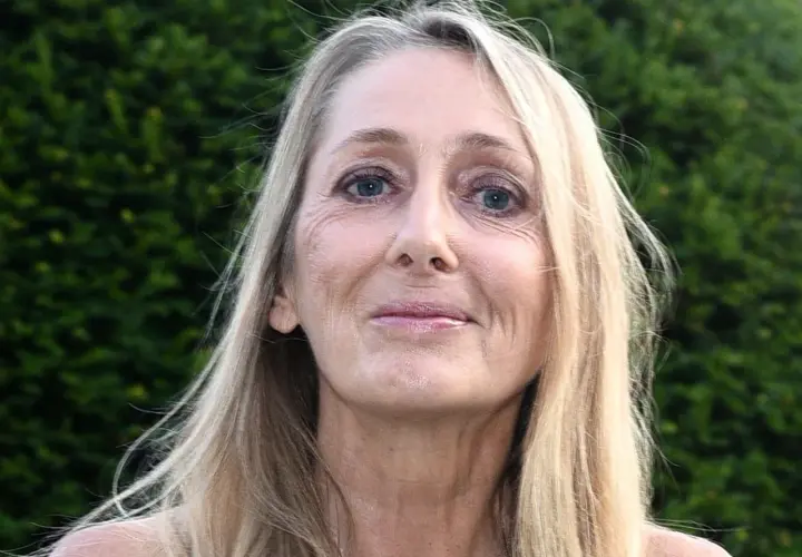 Portret Beaty Pawlikowskiej z blond włosami i niebieskimi oczami na tle zieleni.