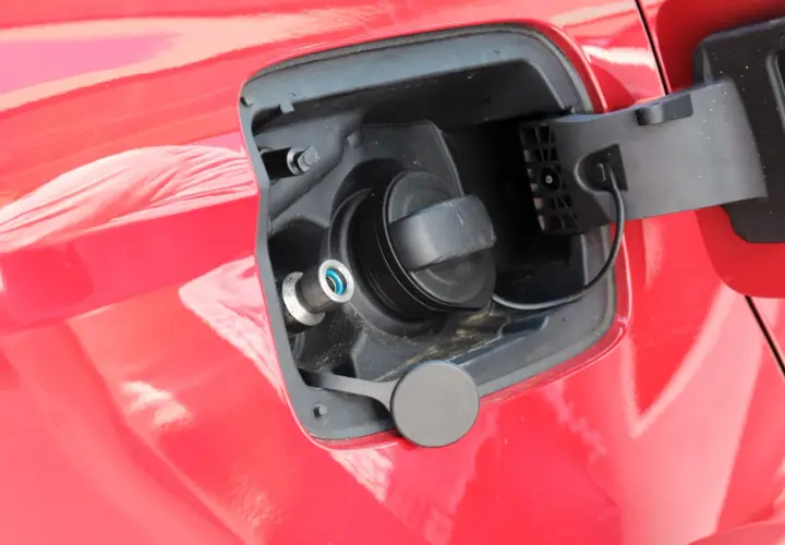 Tapa de combustible de un coche que usa GLP, con boquilla azul y tapón negro.