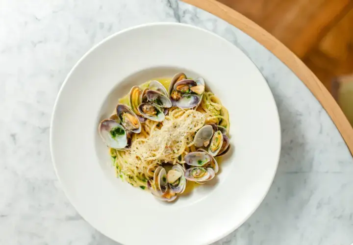 Spaghetti aux coques, une recette italienne savoureuse, garnie de parmesan râpé et d'herbes fraîches.