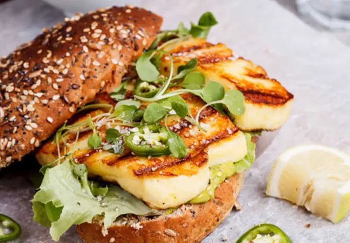 Un délicieux sandwich au halloumi grillé, garni de jalapeños et de jeunes pousses, prêt pour un barbecue estival.