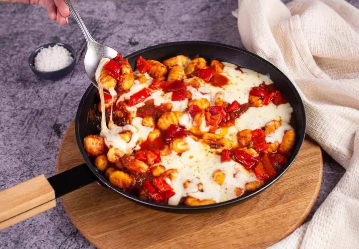 Gnocchis tomate mozza fondants, servis dans une poêle, avec une cuillère qui en prélève une portion filante.