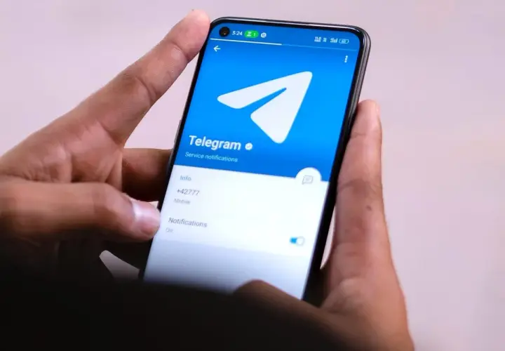 Dłonie trzymają smartfon z otwartą aplikacją Telegram. Widać logo i opcje powiadomień, idealne do dyskretnych rozmów w tajnych grupach Telegram.