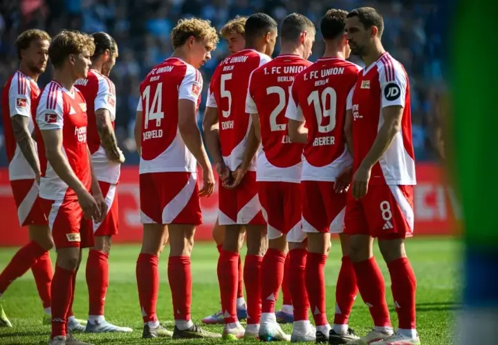 Piłkarze Union Berlin w czerwonych strojach z białymi detalami, w skupieniu przed meczem z Borussią.