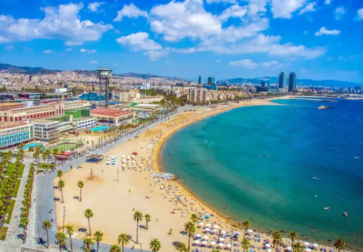 Vista aérea de la playa de la Barceloneta, una de las mejores playas de Barcelona, con gente disfrutando del sol y el mar.