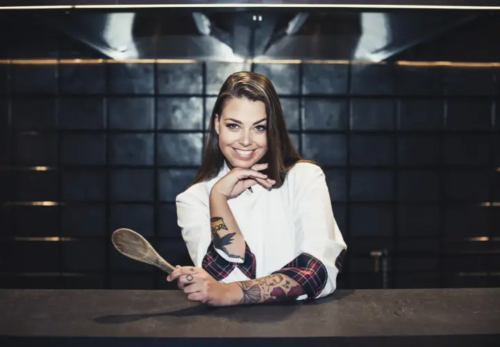Adriana Marczewska, młoda kucharka z tatuażami, trzyma drewnianą łyżkę.