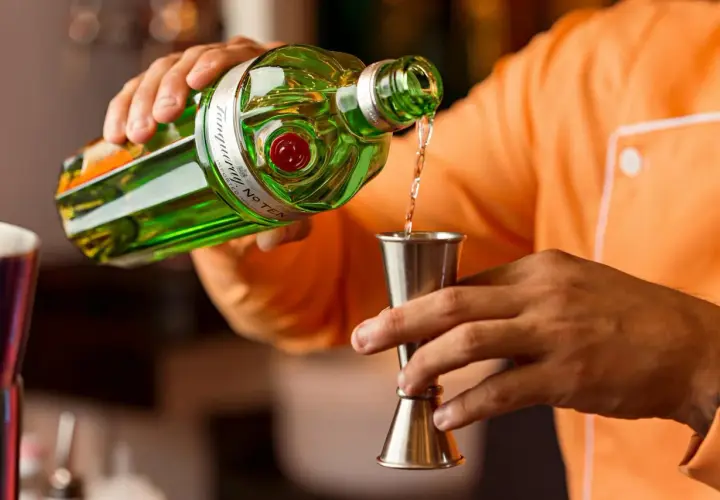 Barman nalewa gin do jiggera. Standardowy shot to 45 ml, a jigger barmański ma proporcje 25/50 ml.