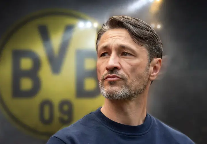 Twarz trenera Borussii Dortmund, z charakterystycznym logo klubu w tle.