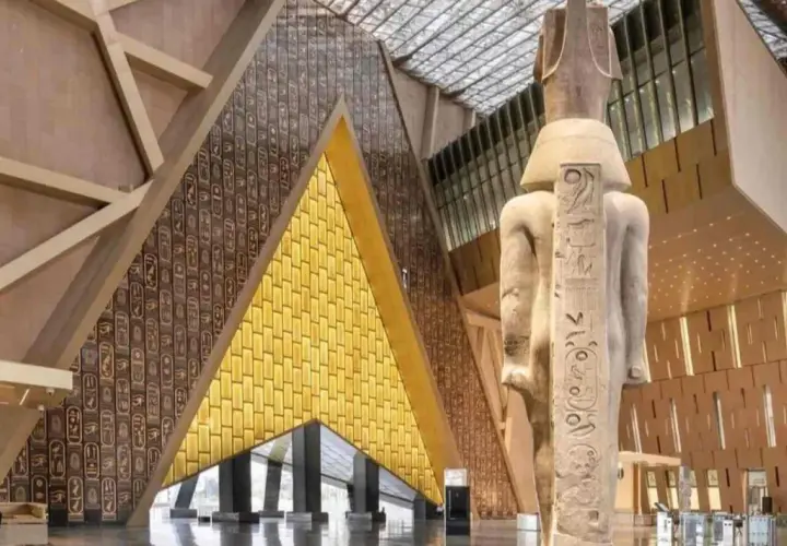 Wielki posąg faraona w nowoczesnym wnętrzu nowego muzeum w Egipcie. Ściany zdobią hieroglify i złote panele.