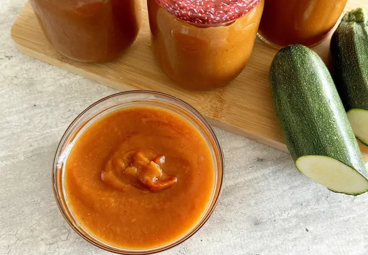 Domowy ketchup z cukinii siostry Anastazji w słoikach i miseczce, obok świeże cukinie.