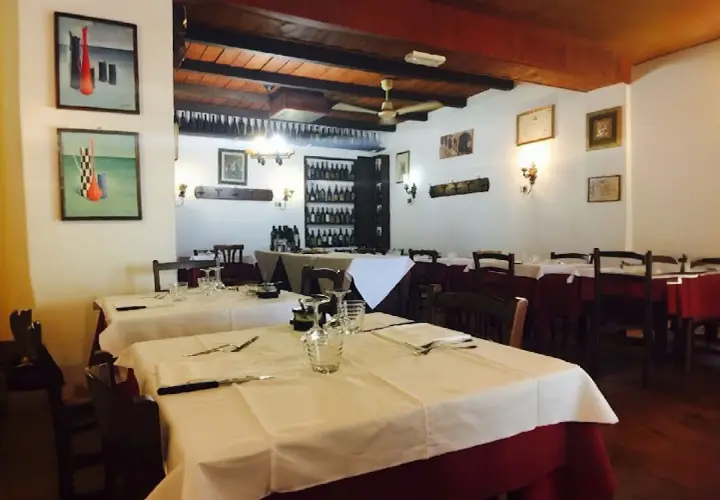 Interno di uno dei ristoranti di Ferrara, con tavoli apparecchiati e quadri alle pareti.