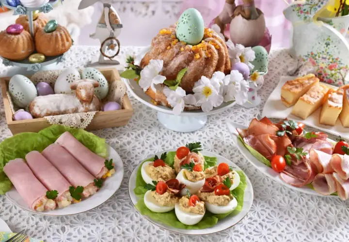 Wielkanocny stół pełen smakołyków: babka, jajka faszerowane, wędliny, ciasto. Idealne inspiracje, co ugotować na święta.