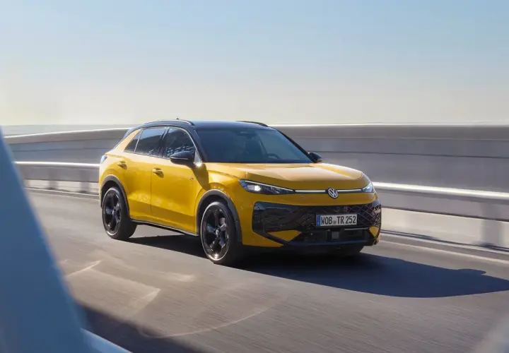 Żółty Volkswagen Cross pędzi po drodze, błyszcząc w słońcu.
