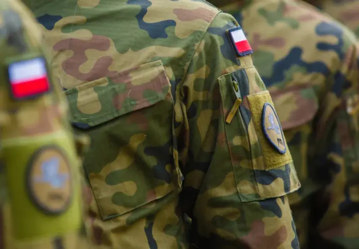 Żołnierz RP w mundurze moro, z naszywką z polską flagą. Dumnie reprezentuje kraj.