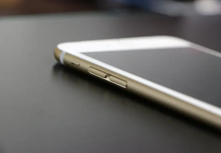 Złoty telefon leży na ciemnym blacie. Dowiedz się, jak sprawdzić lokalizację telefonu, by mieć pewność, że jest bezpieczny.