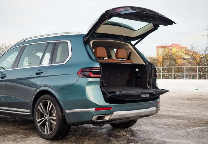 Zielony BMW X7 z otwartym bagażnikiem, gotowy na podróż. Sprawdź aktualną bmw x7 cena.