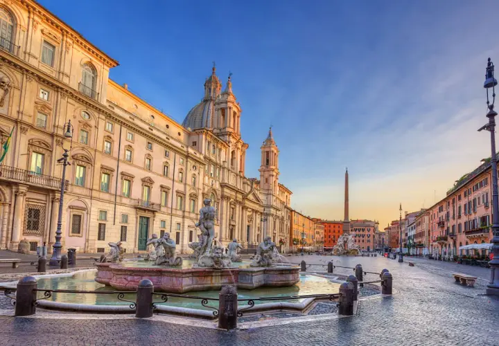 Fontana dei Quattro Fiumi e la chiesa di Sant'Agnese in Agone, simboli della piazza Navona storia, sotto un cielo al tramonto.