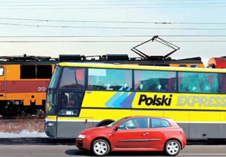 Pociąg i żółty autobus "Polski Express" jadą obok siebie. Czerwony samochód na pierwszym planie. Podróż z Poznania do Lublina?