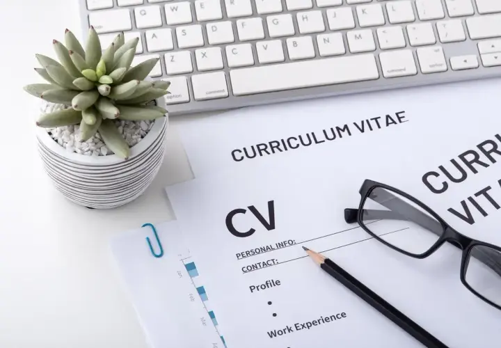 Na biurku leżą dokumenty CV, klawiatura i okulary. To miejsce pracy, gdzie liczy się wykształcenie i doświadczenie.