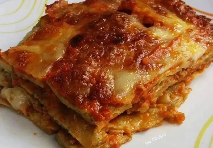 Una fetta di melanzane alla parmigiana, stratificata e dorata, con formaggio filante e sugo rosso.