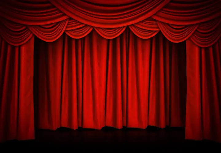 Czerwona, teatralna kurtyna w teatrze, z bogatymi drapowaniami u góry, gotowa do odsłonięcia sceny.