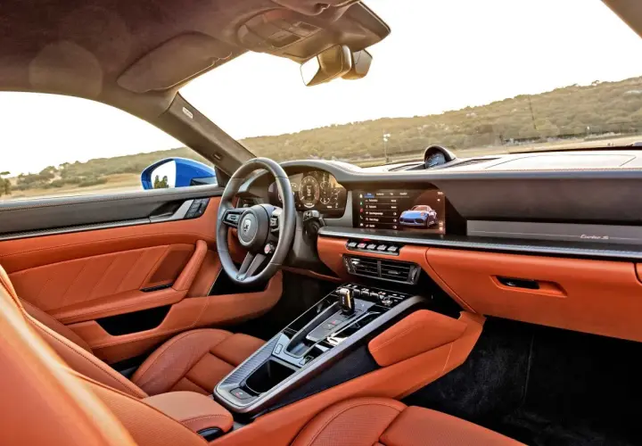 Wnętrze Porsche 911 GTS w kolorze pomarańczowym, z nowoczesnym kokpitem i ekranem multimedialnym.