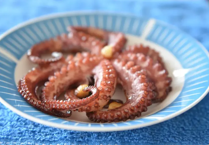 Gotowy ośmiorniczki przepis na talerzu. Delikatne macki z czosnkiem, gotowe do podania.
