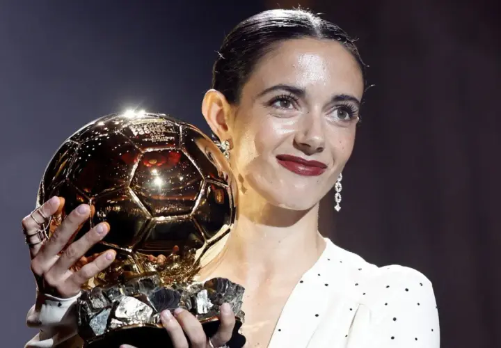 Piłkarka z dumą trzyma złotą piłkę kobiet, symbol najwyższego uznania w świecie futbolu.