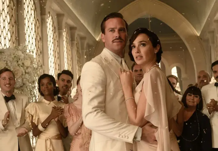 Śmierć na Nilu obsada: Armie Hammer i Gal Gadot w eleganckich strojach, otoczeni przez innych aktorów, podczas uroczystości.