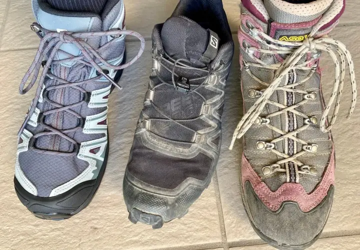 Three hiking boots: a low-cut grey boot, a mid-cut black boot, and a high-cut grey and pink boot.