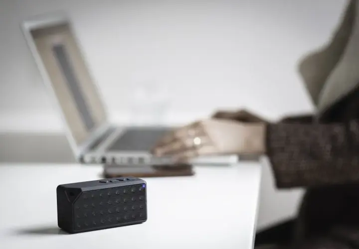 Mały głośnik z niebieską diodą obok laptopa. Dowiedz się, jak sprawdzić, czy komputer ma Bluetooth.