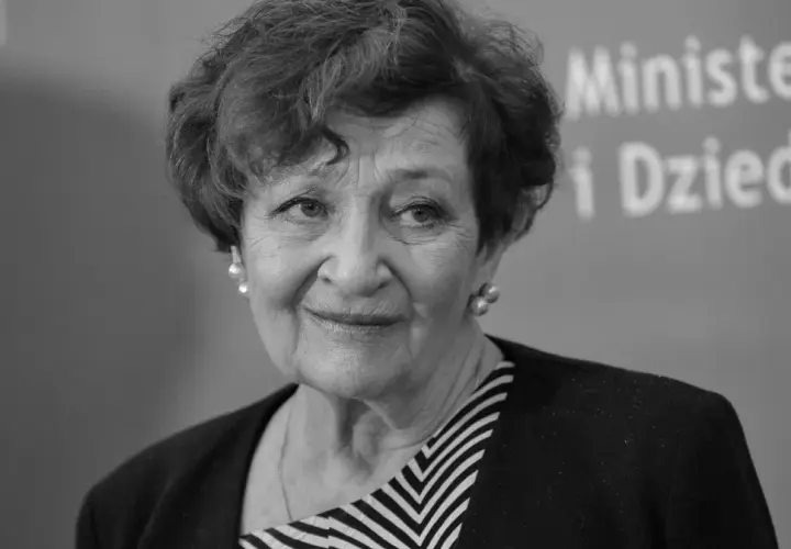 Uśmiechnięta Ewa Dałkowska, aktorka znana z wielu filmów, w eleganckiej stylizacji.
