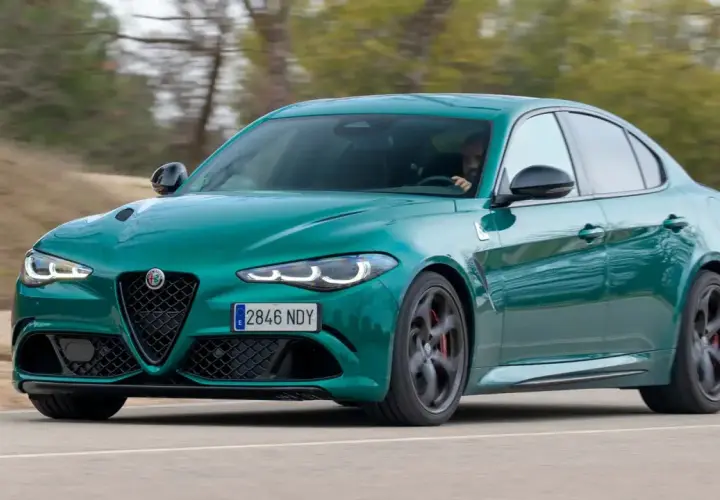 Un Alfa Romeo Giulia verde es conducido en una carretera, con el conductor visible al volante. Es una prueba del coche.