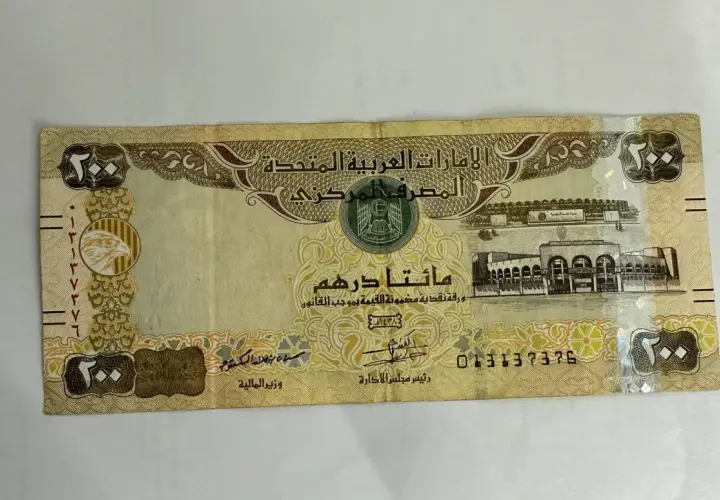 Banknot 200 dirhamów, waluta w Dubaju, z wizerunkiem sokoła i budynków.