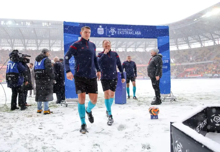 Sędziowie w śnieżny dzień wchodzą na boisko przed meczem Jagiellonia Białystok – GKS Katowice.