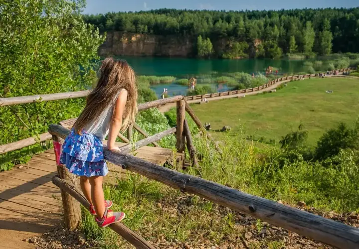 Dziewczynka podziwia widok na zalew w Parku Gródek Jaworzno. Warto sprawdzić park gródek jaworzno cena wstępu, by cieszyć się tym miejscem.