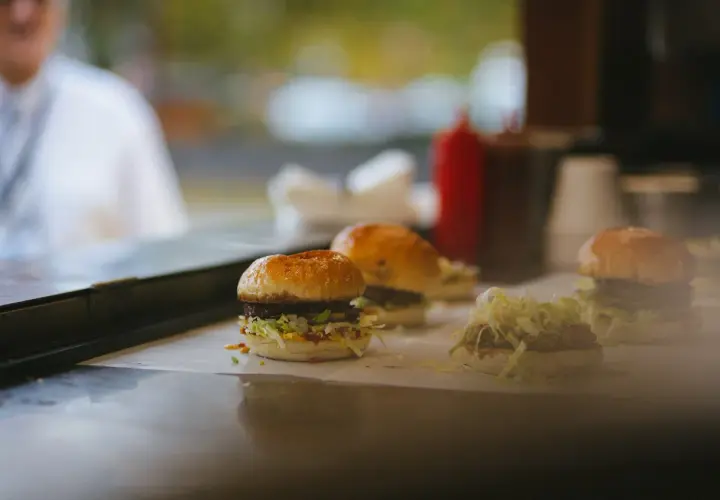 Trzy soczyste burgery, prawdziwe bomby kaloryczne na przytycie, gotowe do podania.
