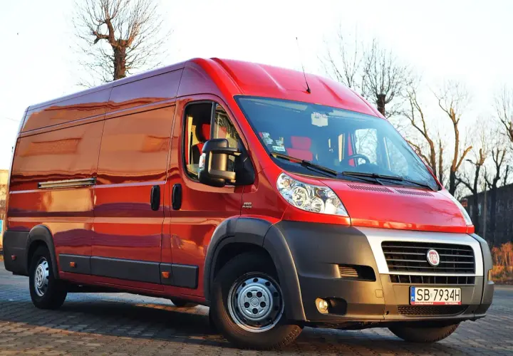 Czerwony Fiat Ducato Maxi zaparkowany na zewnątrz, gotowy do transportu.