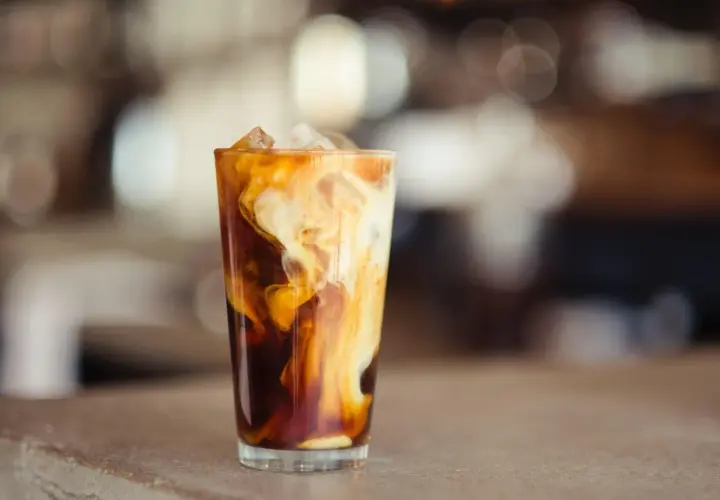 Ein Glas Eiskaffee mit Milchwirbeln und Eiswürfeln. Perfekt für ein iced coffee rezept schnell an heißen Tagen.