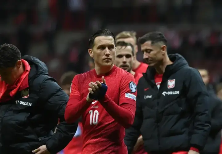 Piłkarze reprezentacji Polski, w tym Lewandowski, w czerwonych strojach i czarnych kurtkach, z nadzieją patrzą w przyszłość, marząc o baraze ms 2026.