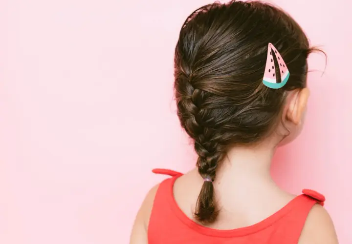 Niña con un bonito peinado de trenza y un pasador de sandía.