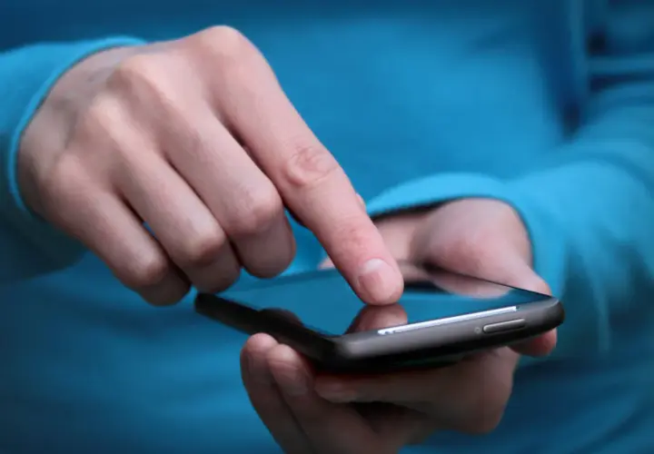 Palec dotyka ekranu smartfona, szukając rozwiązania, jak wyłączyć tryb awaryjny w telefonie.