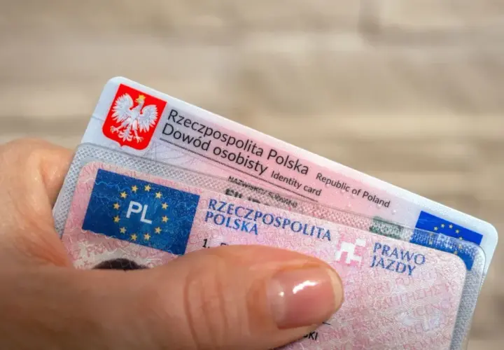 Dłoń trzyma polski dowód osobisty i prawo jazdy. To ważne dokumenty, które pozwalają na swobodne podróżowanie, a prawo jazdy bezterminowe daje spokój na lata.