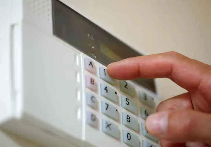 Dłoń naciska klawisz "1" na klawiaturze panelu alarmowego. To pokazuje, jak działa alarm w domu – wprowadzanie kodu.