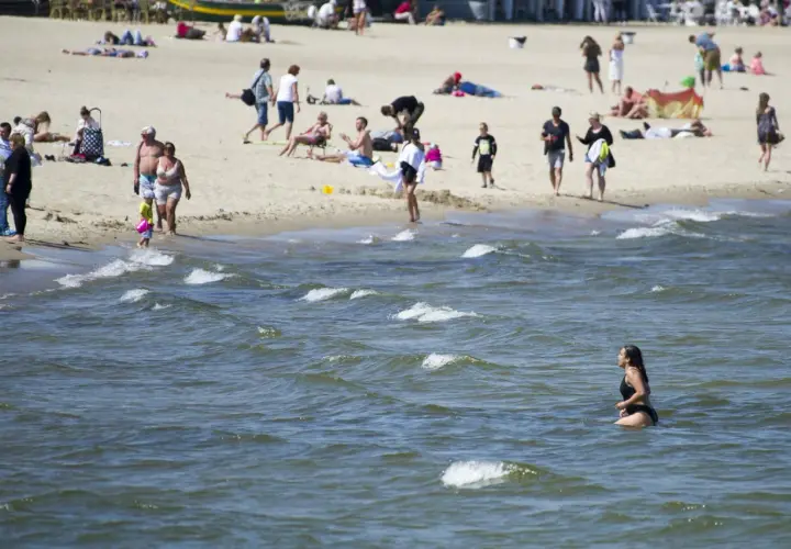 Plaża pełna ludzi, a w wodzie kąpie się kobieta. Warto sprawdzić, ile stopni ma Bałtyk latem, by móc cieszyć się takimi widokami.