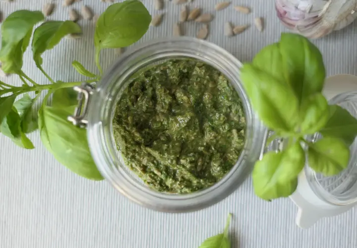 Domowe pesto z bazylii w słoiku, obok nasion słonecznika i czosnku. Idealne, by dowiedzieć się, jak zrobić pesto.