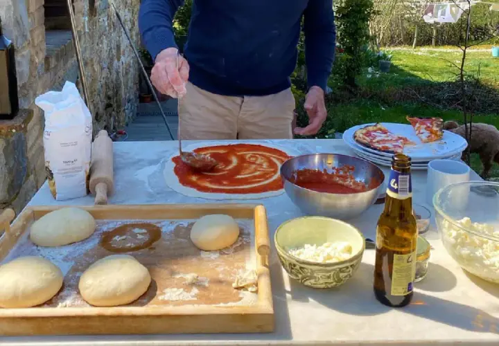Przygotowanie pizzy w słonecznym Chianti, Włochy. Ciasto, sos pomidorowy i ser czekają na pieczenie.