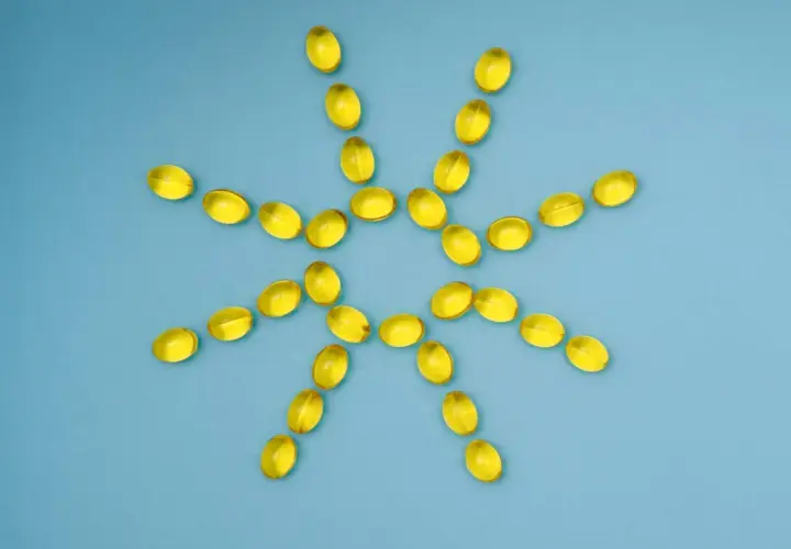 Gelbe Kapseln bilden eine Sonne, die gegen Winterdepression hilft. Vitamin D für mehr Licht.