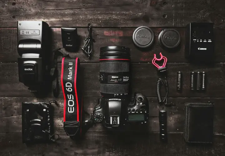 Zestaw sprzętu fotograficznego: aparat Canon EOS 6D Mark II, obiektyw Canon, lampa błyskowa Godox, akcesoria. Różne marki aparatów fotograficznych w jednym ujęciu.