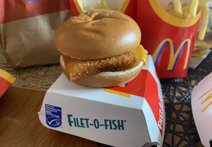 Filet-o-Fish, klasyczny fishburger z McDonald's, na białym pudełku z logo MSC. Obok frytki w czerwonym opakowaniu.